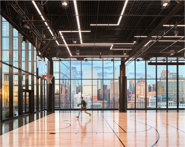 Una cancha de baloncesto en un edificio coorporativo con grandes ventanas.